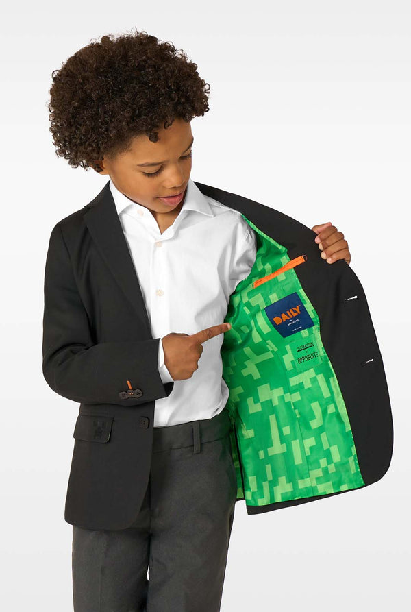 Child wearing a black blazer with a green patterned lining, pointing to the lining.