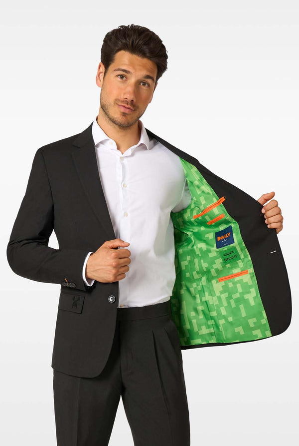 Man wearing a black suit with a green and orange patterned vest on a white background