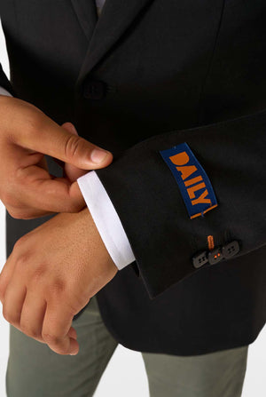 Person adjusting a cuff on a black suit with 'DAILY' branding.