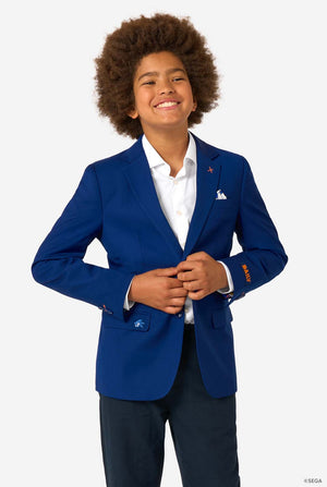 Child wearing a blue blazer with a white shirt and dark pants on a light gray background