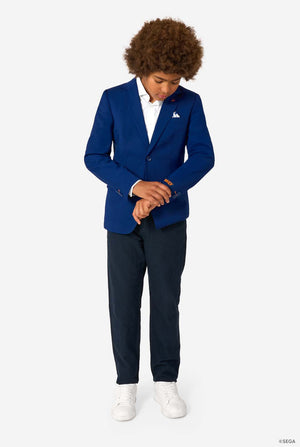 Person wearing a blue blazer and navy pants on a grey background