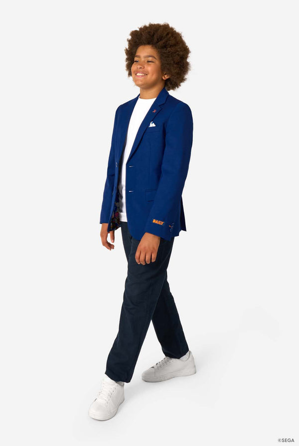 Person wearing a blue blazer with a logo, white shirt, navy pants, and white sneakers on a white background.