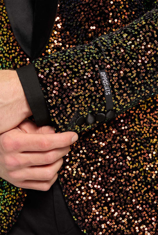 This image showcases a stylish men’s dinner jacket from OppoSuits Deluxe collection, featuring dazzling amber sequins that create a shimmering effect. The sequin blazer has a sleek satin lapel, a tailored fit. The model pairs it with a classic black dress shirt and bow tie, making this jacket perfect for formal events, holiday parties, or New Year celebrations. Ideal for men who want to stand out with bold, luxurious, and festive attire. Sleeve close up.