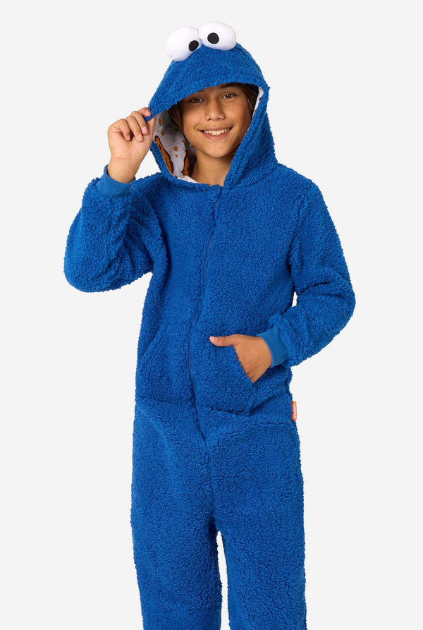 A kid is wearing a blue sesame street onesie resembling Cookie Monster. 