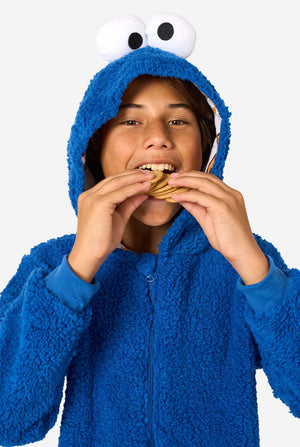A kid is wearing a blue sesame street onesie resembling Cookie Monster. 