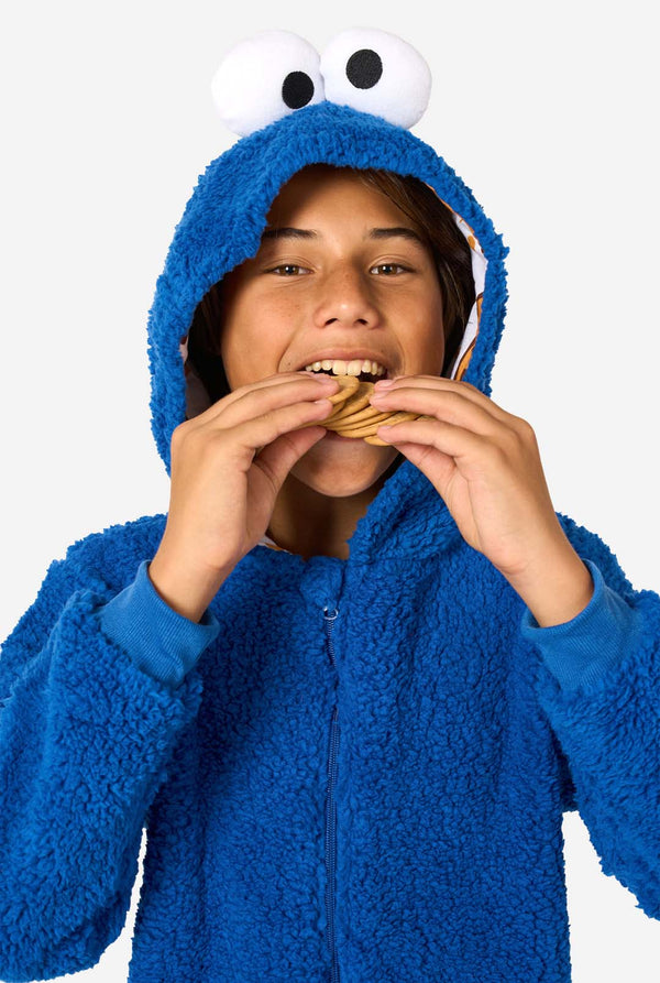 A kid is wearing a blue sesame street onesie resembling Cookie Monster. 