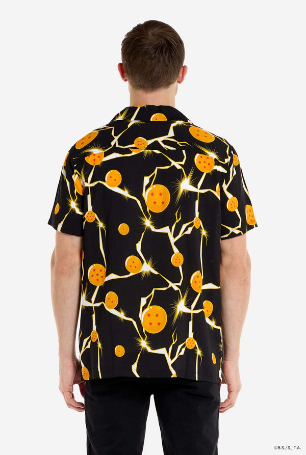 Man wearing black Hawaiian shirt with Dragon Ball Z print, showings Dragon Balls and lighting. He is also wearing a white t-shirt and black pants. View from the back.