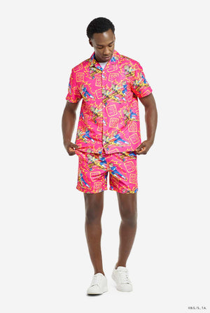 Man wearing pink summer set consisting of shirts and shorts. Summer set has Dragon Ball Z Goku and Vegeta fighting print. Full body image.