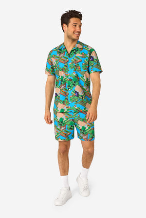 A man wearing a colorful summer outfit featuring a Minecraft Overworld print, showcasing pixelated landscapes, characters, and elements from the iconic game. The short-sleeve shirt and matching shorts highlight a vibrant design inspired by the Minecraft universe. Full body image