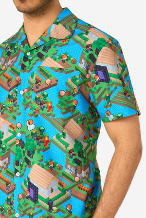 A man wearing a colorful summer outfit featuring a Minecraft Overworld print, showcasing pixelated landscapes, characters, and elements from the iconic game. The short-sleeve shirt and matching shorts highlight a vibrant design inspired by the Minecraft universe. Close-up chest