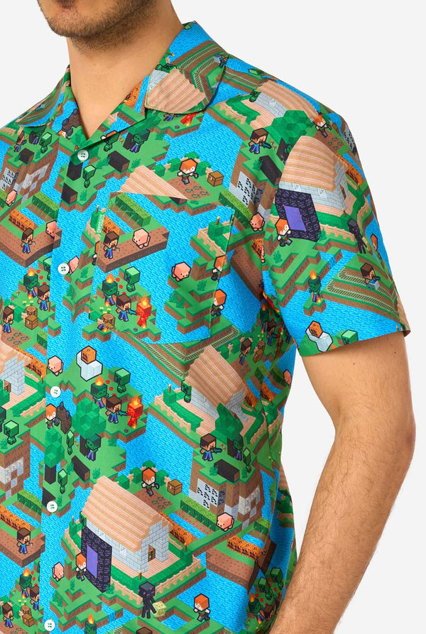 A man wearing a colorful summer outfit featuring a Minecraft Overworld print, showcasing pixelated landscapes, characters, and elements from the iconic game. The short-sleeve shirt and matching shorts highlight a vibrant design inspired by the Minecraft universe. Close-up chest