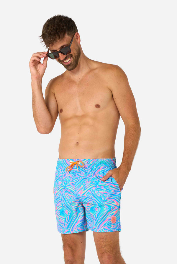 Man wearing a men's vibrant holographic swim shorts with a mesmerizing blue, pink, and purple swirl design. Eye-catching and stylish swimwear for summer fun.