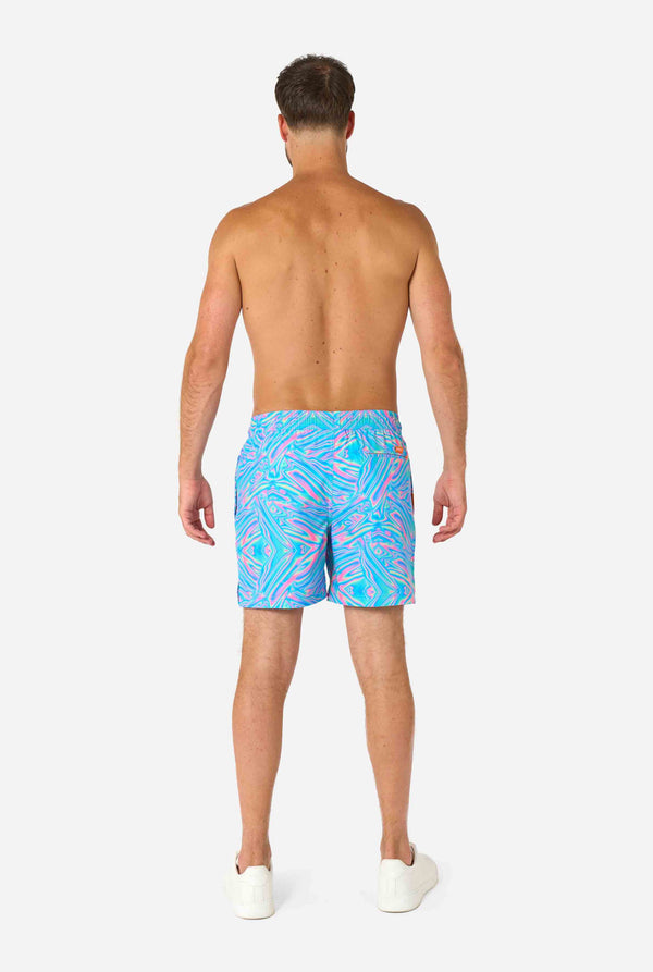 Man wearing a men's vibrant holographic swim shorts with a mesmerizing blue, pink, and purple swirl design. Eye-catching and stylish swimwear for summer fun.
