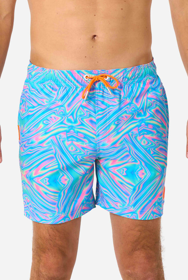 Man wearing a men's vibrant holographic swim shorts with a mesmerizing blue, pink, and purple swirl design. Eye-catching and stylish swimwear for summer fun.