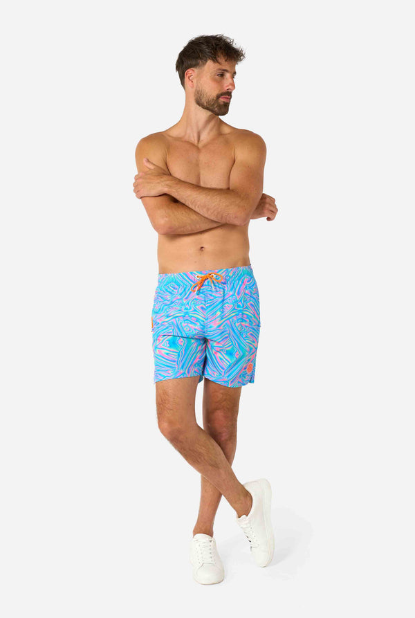 Man wearing a men's vibrant holographic swim shorts with a mesmerizing blue, pink, and purple swirl design. Eye-catching and stylish swimwear for summer fun.