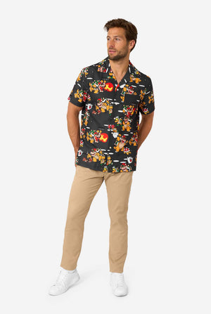 Man posing in Bowser’s Mayhem short-sleeve shirt with beige pants and sneakers.