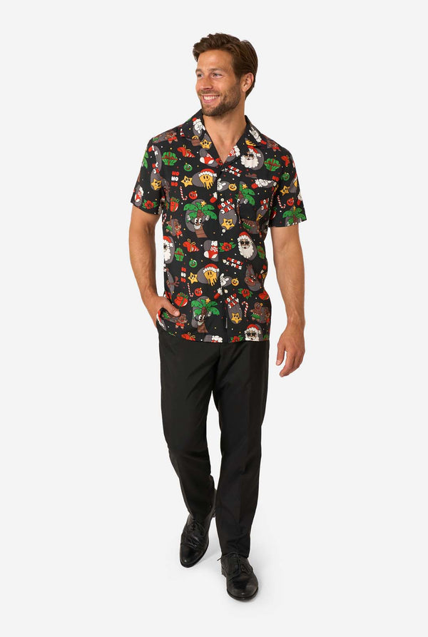Man wearing a colorful, patterned Christmas shirt on a white background. Full body image