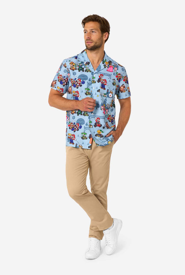 Man wearing light blue short-sleeve Mario Kart shirt with colorful character print. Full body image.