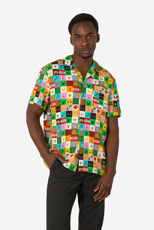 Man wearing a colorful Minecraft Hawaiian shirt featuring pixelated blocks, characters, and items from the game, paired with black pants, standing against a plain white background.