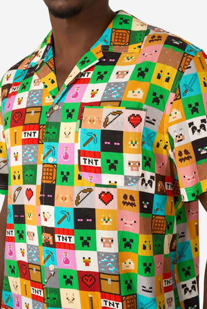 Man wearing a colorful Minecraft Hawaiian shirt featuring pixelated blocks, characters, and items from the game, paired with black pants, standing against a plain white background. Close up of the chest