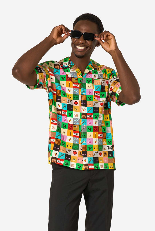 Man wearing a colorful Minecraft Hawaiian shirt featuring pixelated blocks, characters, and items from the game, paired with black pants, standing against a plain white background. Wearing sunglasses