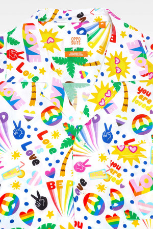 Image of a white Hawaiian shirt with a rainbow pride print. The Print consists of peace symbols, hearts, and other icons. 