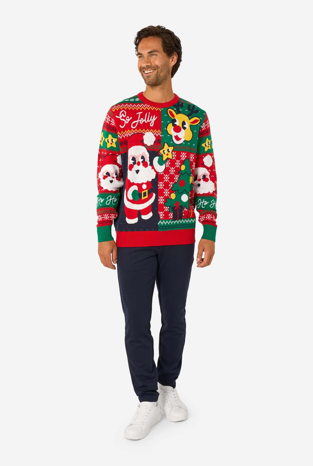 Smiling man wearing a colorful knitted Christmas sweater featuring Santa Claus, Rudolph, and the text “So Jolly.”