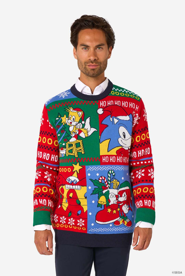Man wearing a colorful knitted Christmas sweater featuring Sonic and friends in festive holiday scenes.