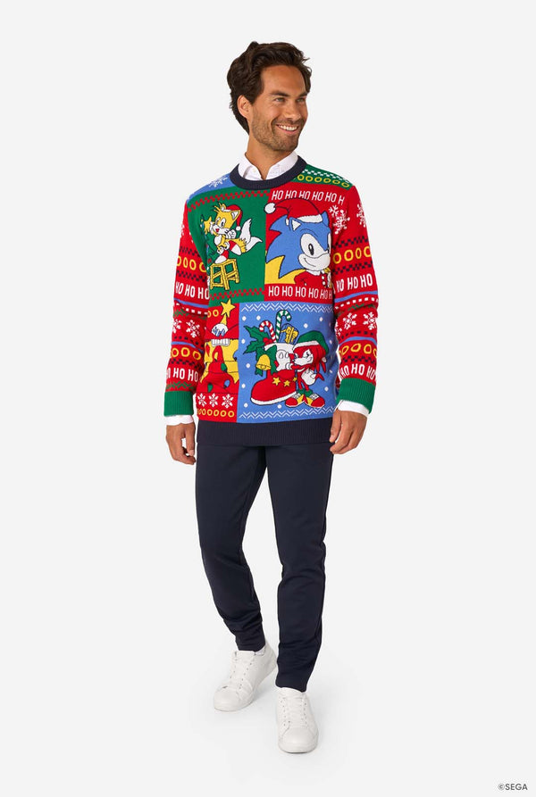Man wearing a colorful knitted Christmas sweater featuring Sonic and friends in festive holiday scenes. Full body image.
