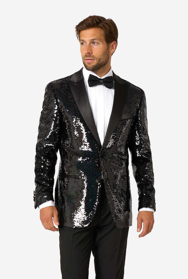 Man wearing a black sequin tuxedo with satin lapels, white dress shirt, and black bow tie, looking slightly to the side.