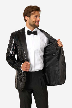 Man in a black sequin tuxedo holding it open to reveal a plain black interior lining with an OppoSuits label.