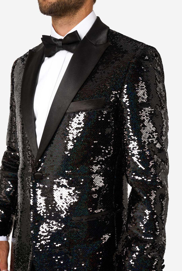 Close-up of upper body wearing a black sequin tuxedo jacket with satin lapels, white dress shirt, and black bow tie.