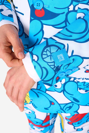 Teen boy wearing a vibrant Smurfs kids suit with colorful cartoon character prints in blue, red, yellow, and white, paired with a matching tie and white shirt, smiling against a plain background. Sleeve close up.