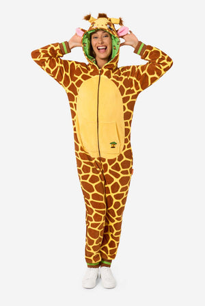 A smiling woman is wearing a brown and yellow adult onesie designed as a giraffe. The onesie features a hood resembling a Giraffes head, and giraffe details, perfect for cozy lounging or costume parties. 