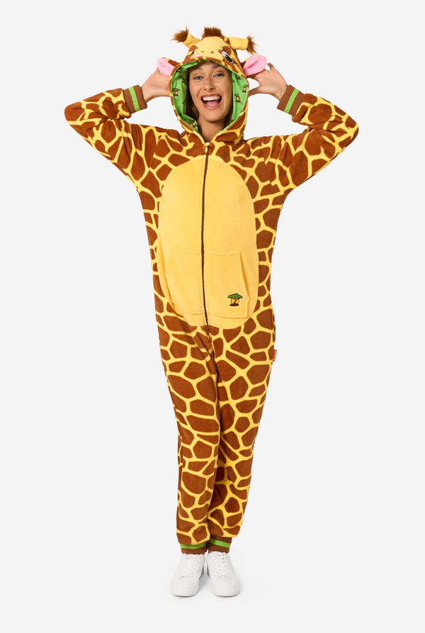 A smiling woman is wearing a brown and yellow adult onesie designed as a giraffe. The onesie features a hood resembling a Giraffes head, and giraffe details, perfect for cozy lounging or costume parties. 