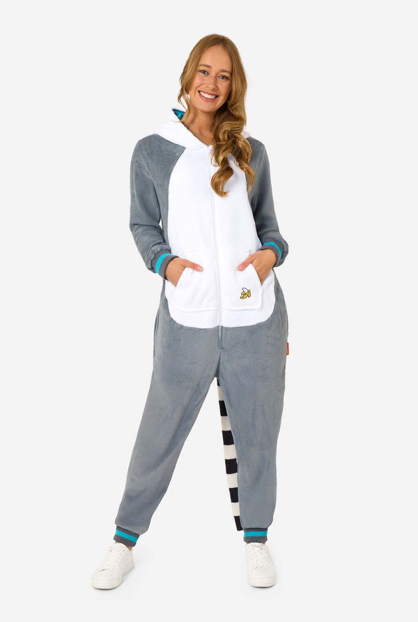 A women is wearing a grey and white lemur adult onesie featuring playful hood details and cozy, soft material, perfect for lounging or costume events. Including black and white tail. The hood is on her back. Full body image.