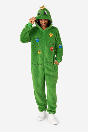 A smiling man wearing a green Christmas onesie designed to look like a Christmas tree, decorated with cartoon ornaments and stars. Hood on it's head, full body image
