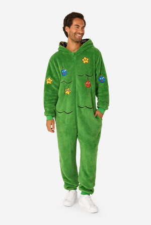 A smiling man wearing a green Christmas onesie designed to look like a Christmas tree, decorated with cartoon ornaments and stars. Full body image