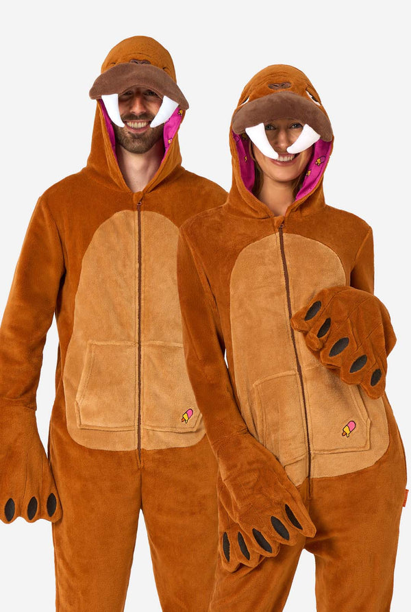 A cheerful man and women are wearing a brown adult onesie designed as a walrus. The onesie features a hood with fangs, stitched gloves resembling paws, and playful walrus details, perfect for cozy lounging or costume parties. The hood are on their heads.