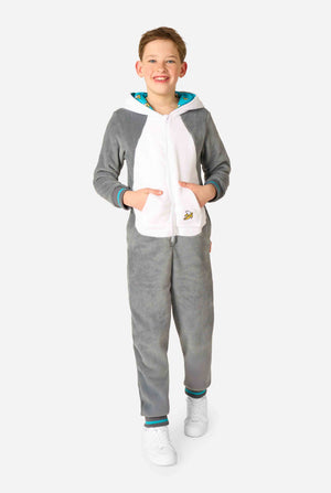 Child wearing a cozy unisex kids onesie designed as a lemur, featuring grey and white plush fabric, a hood with a cartoon lemur face and ears, and a playful banana print on the pocket. Full body.