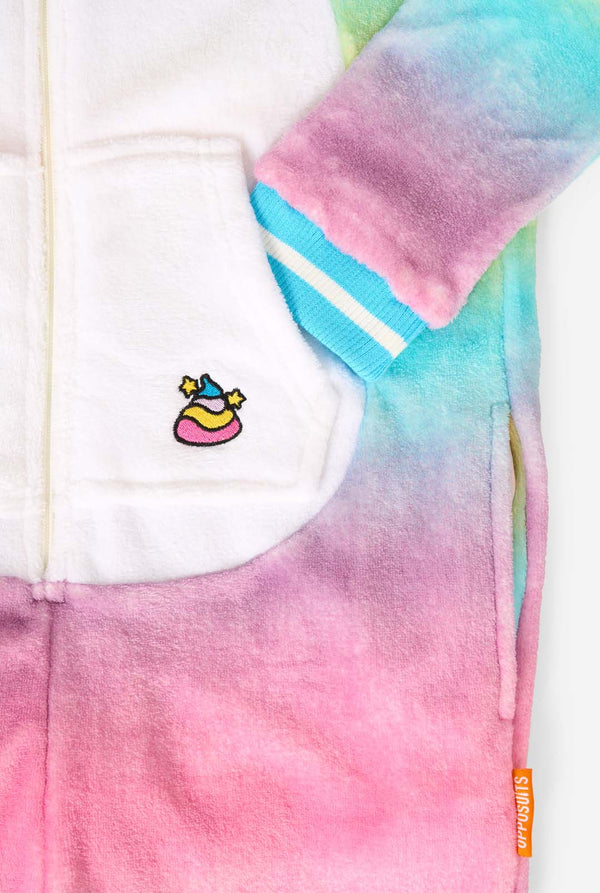 A child stands modeling a soft, hooded unicorn onesie that features a bright, pastel rainbow color gradient on the arms and legs and a white front panel. Close up of the pockets
