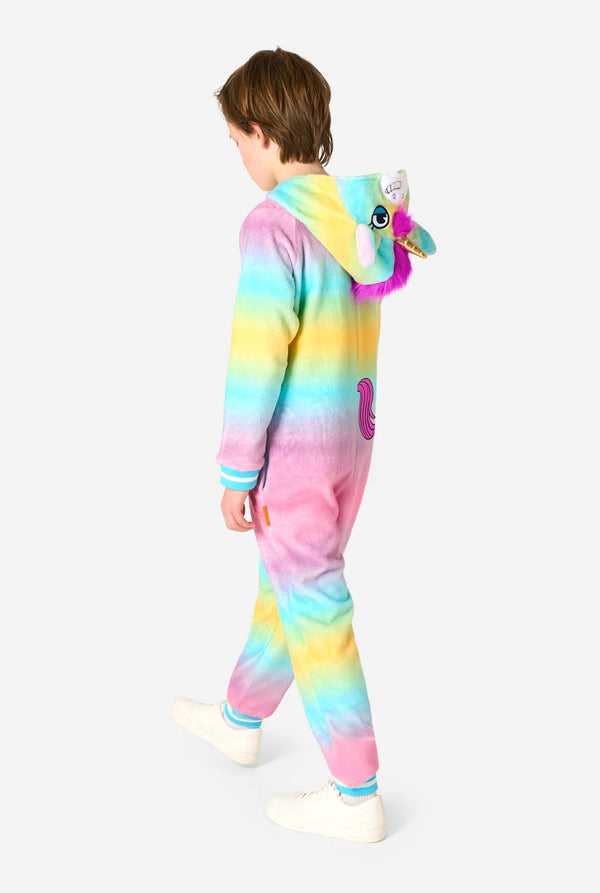 A child stands modeling a soft, hooded unicorn onesie that features a bright, pastel rainbow color gradient on the arms and legs and a white front panel. Full body image