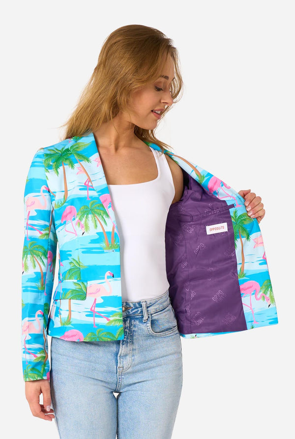 Image with a light background and a woman wearing a light blue blazer with tropical flamingo print and jeans. Holding one side of the jacket open.