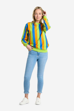 Woman wearing a colorful striped sweater and light blue jeans on a white background