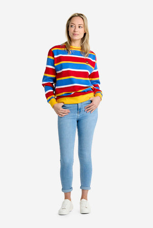 Person wearing a colorful striped sweater and light blue jeans on a white background