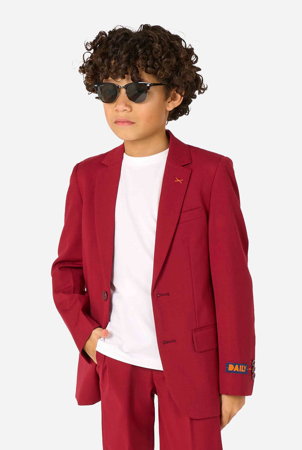 Kid wearing a stylish burgundy red suit with a white dress shirt, looking confidently. Perfect formal outfit for boys' special occasions, weddings, and parties.