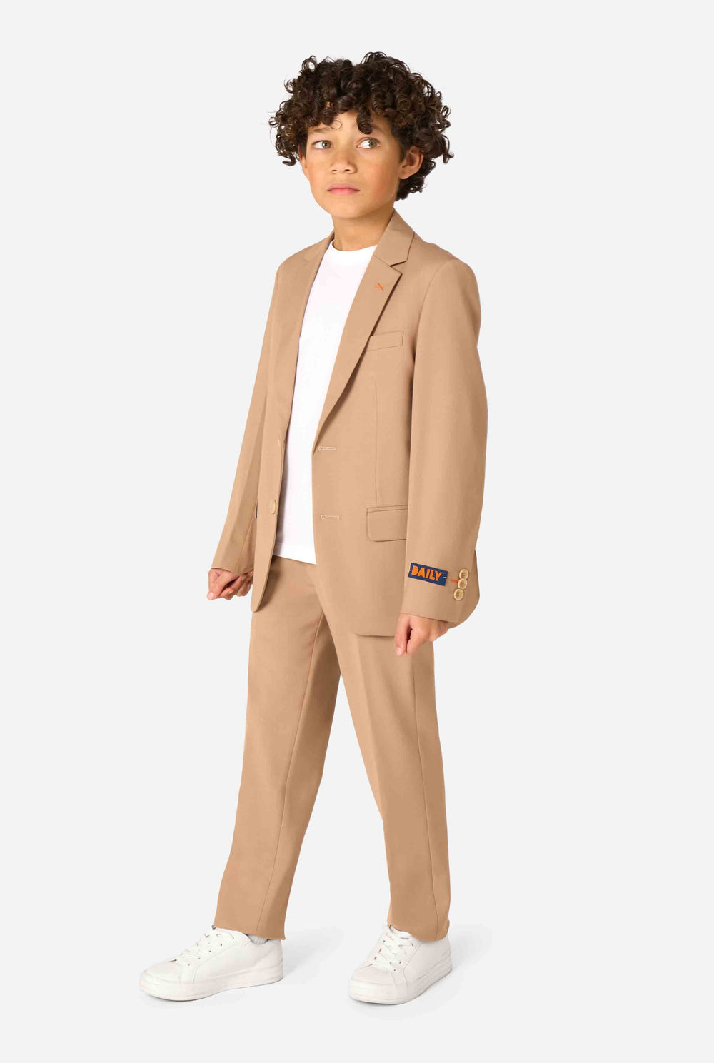 Kid wearing a stylish light brown/ beige suit with a white dress shirt, looking away from the camera. Perfect formal outfit for boys' special occasions, weddings, and parties.