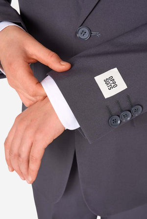 Teen boy wearing a stylish charcoal colored grey suit with a white dress shirt, smiling confidently. Perfect formal outfit for boys' special occasions, weddings, and parties. Sleeve close-up.