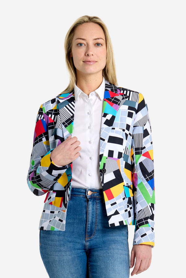 Woman wearing a colorful patterned blazer over a white shirt and blue jeans on a white background