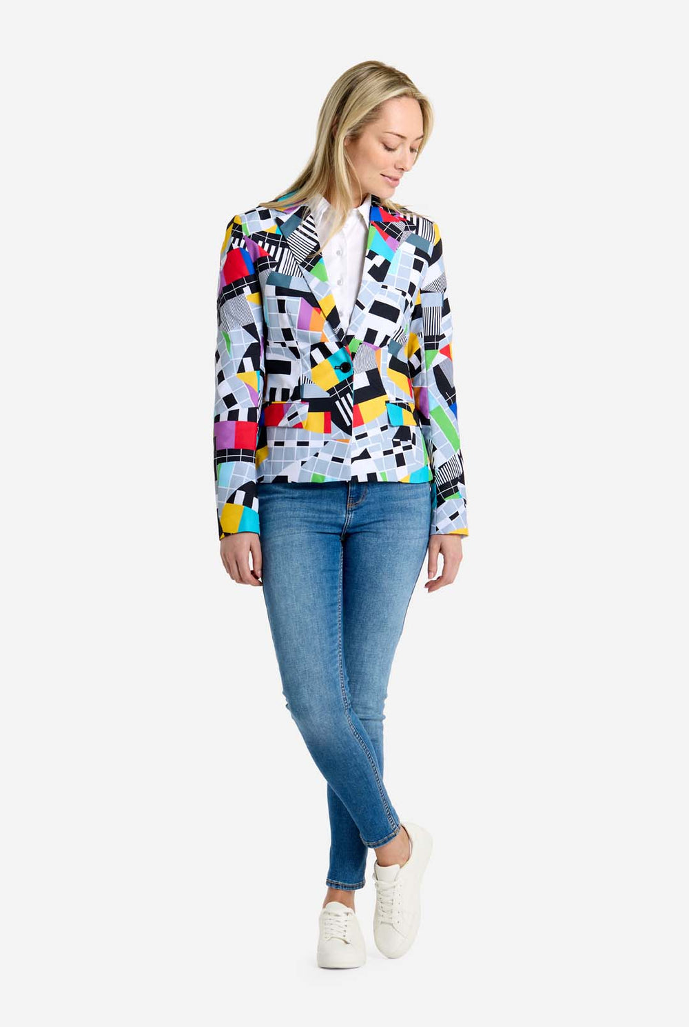 Woman wearing a colorful patterned blazer over a white shirt and blue jeans on a white background